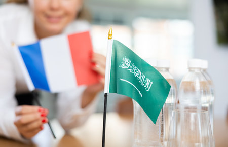 Woman secretary prepares an office for negotiations - she places flags of Saudi Arabia and France tableの写真素材