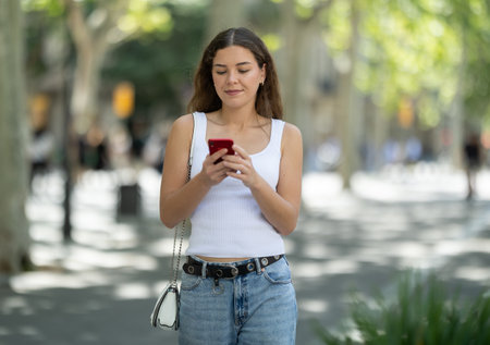 Girl looks at smartphone screen while walkingの写真素材