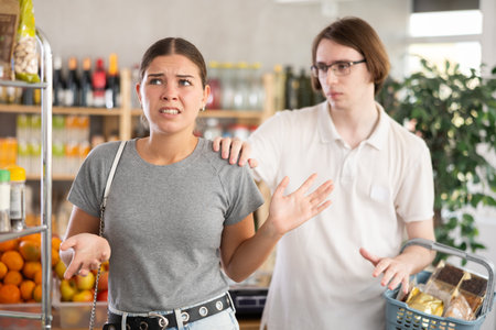 Young man calming irritated woman in grocery storeの写真素材