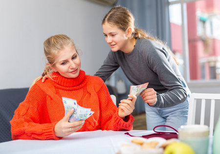 Schoolgirl taking money from her motherの写真素材
