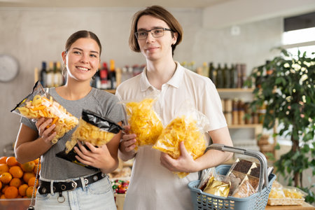 Couple young man and woman choosing chips or snack mixの写真素材