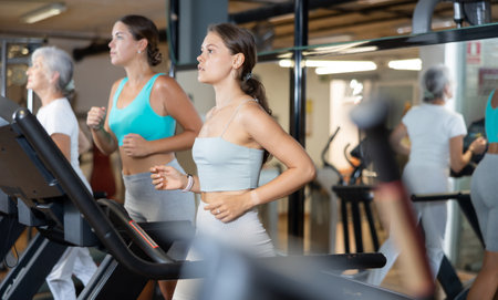 Focused motivated girl leading healthy active lifestyle doing cardio workout in gym, running on treadmillの写真素材