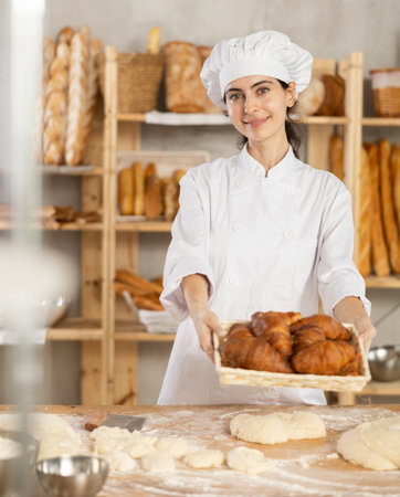 In working room of bakery, there is girl with croissants in wicker basket in handsの写真素材