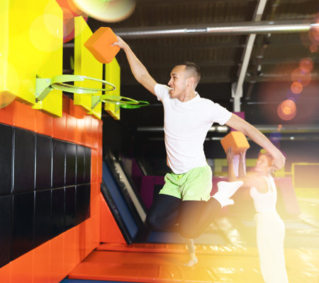 Cheerful man playing basketball with foam cube at trampoline parkの写真素材