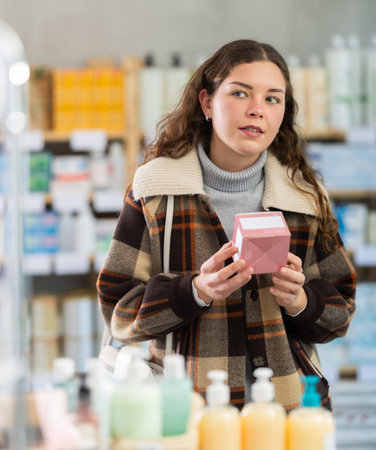 Young woman chooses pills at pharmacyの写真素材