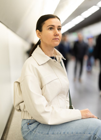 Woman in anticipation of metro train sits on bench at stationの写真素材