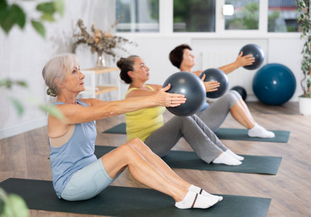 Group of elderly woman doing pilates with soft ball in studioの写真素材