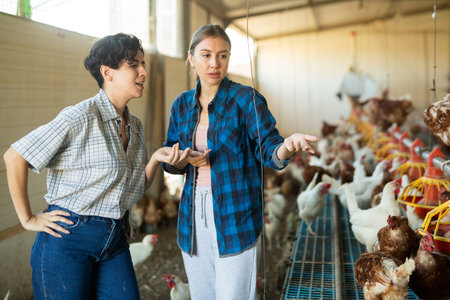 Two female farmers discussing problems in poultry farmの写真素材