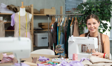Seamstress working on modern sewing machine in sewing workshop