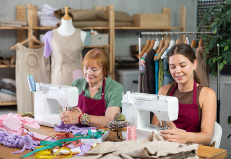 Elderly and young women seamstresses sewing on machine