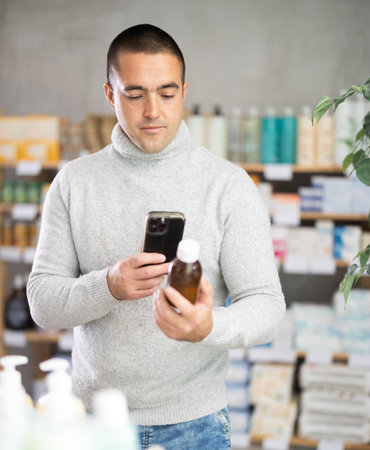 Male buyer scans code on cough syrup to check expiration dateの写真素材