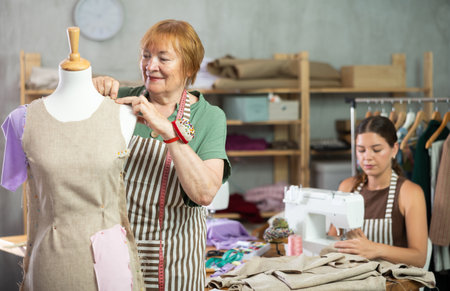 Elderly woman working with mannequin, young woman sewingの写真素材