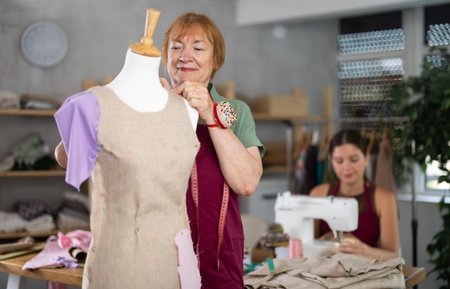 Elderly woman working with mannequin, young woman sewingの写真素材