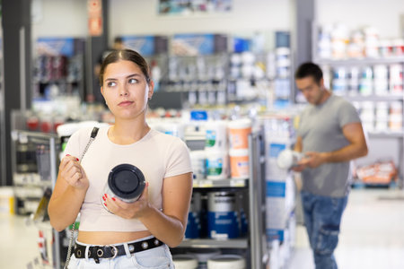 Woman buys paint tin in paintwork material store for carrying out internal finishing work on objectの写真素材