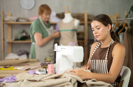 Young woman sews on machine female assistant sews on mannequinの写真素材
