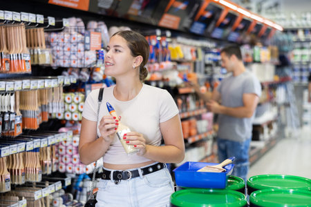 Smiling young woman choosing brushes in local hardware storeの写真素材