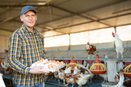 Portrait of man farmer holding eggs in hands in henhouse