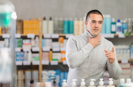 Man pharmacy client suffers from sore throat and coldの写真素材