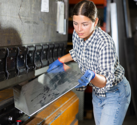 Young woman bends sheet of metal under pressureの写真素材