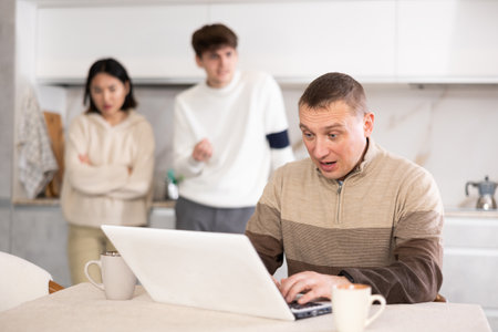 Dissatisfied son and daughter scold their father for playing computer gamesの写真素材
