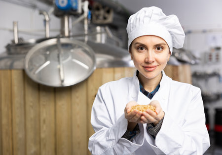 Woman brewer holding fresh barley in her hands on the territory of breweryの写真素材