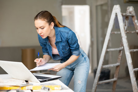 Woman with laptop at house being renovatedの写真素材