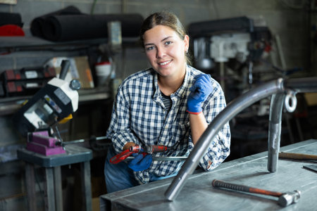 Young woman posing with vice in workshopの写真素材