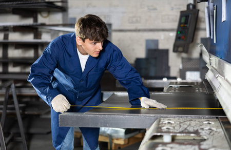 Guy measuring sheet of metal with tape measure