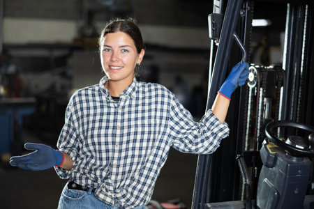 Young woman posing by forklift in workshop