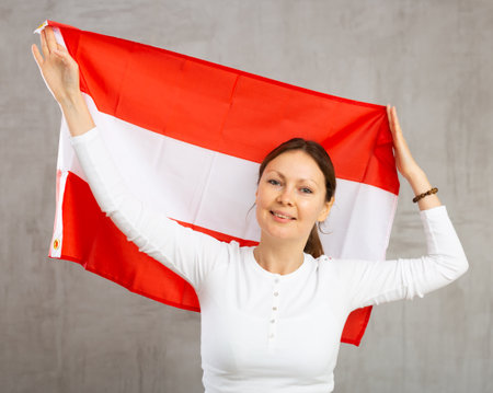 Smiling woman waving national flag of Austria in studioの写真素材