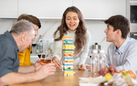 Happy young girl concentrating on removing block from tower while playing jenga, spending free time...