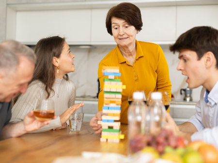 Elderly woman playing jenga during family gathering at homeの写真素材