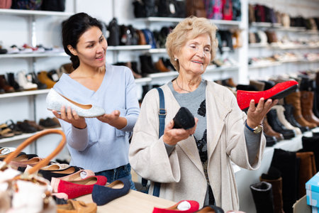 Friendly female sales consultant demonstrates ballet flats to a mature woman customerの写真素材