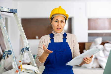 Frustrated woman builder checking project documentationの写真素材