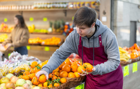 Young salesman lays out tangerines on counterの写真素材