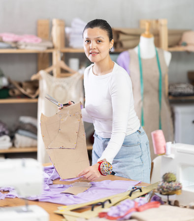 woman tailor holds patterns for clothes in her hands