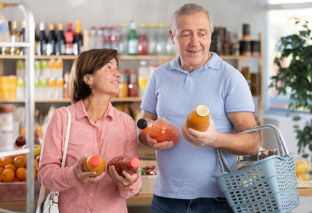 Couple elderly man and woman choosing juices in grocery storeの写真素材