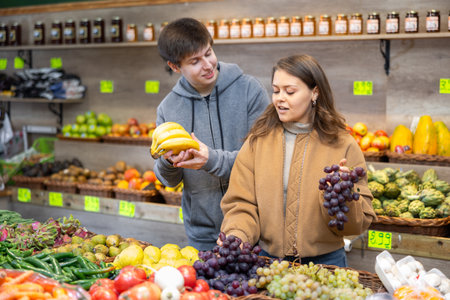 Young woman and young guy choose grapes and bananasの写真素材