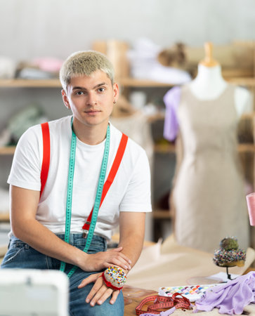 Male tailor stands in the workshop against the background of shelvesの写真素材