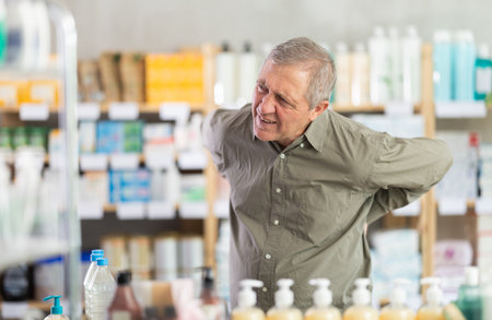 Senior man visits pharmacy and suffers from backacheの写真素材