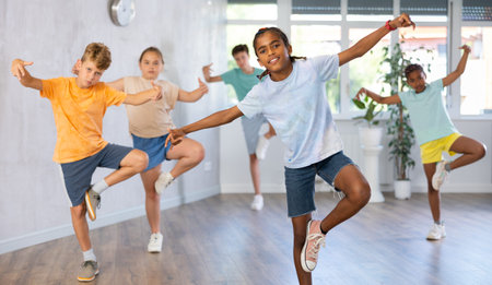 Girls and boys doing dance workout during group class in fitness center