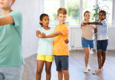 Multinational boys and girls enjoying active dance in studio