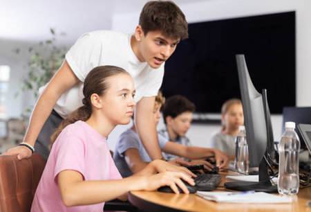 Preteen girl learning computer programs with teacher in training room