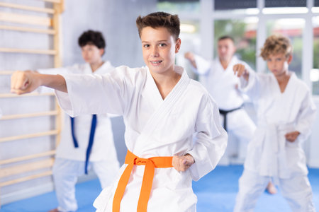Preteen attendee of karate classes practicing kata standing in row with othersの写真素材