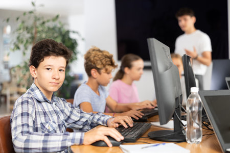 Portrait of male teenage student at computer in school classの写真素材
