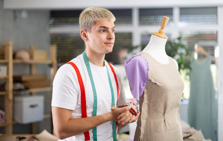 Young male tailor working with mannequin