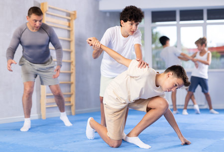 Diligent preteen student twisting his opponents arm in sports hallの写真素材