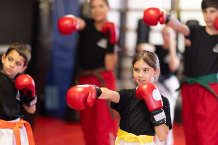 Group of children in boxing gloves are training in gym