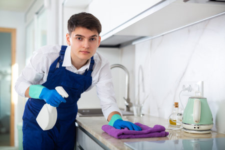 Male professional cleaner cleaning kitchen countertop