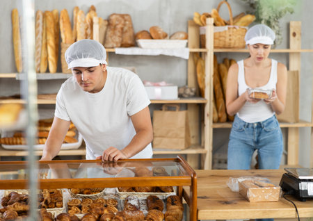 Young guy taking pastry in self-service bakery shopの写真素材